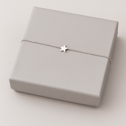 bracelet minimaliste avec étoile en acier inoxydable argenté présenté sur une boîte cadeau grise