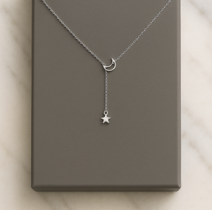Collier en forme de Y avec pendentif lune et étoile en acier inoxydable argenté posé sur boîte grise