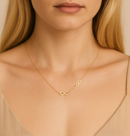 Collier infini doré porté par une femme, avec deux symboles sur chaîne fine