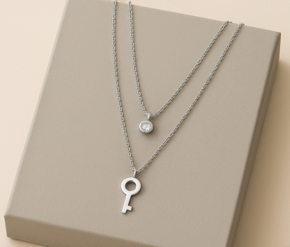 Collier clé argenté en acier inoxydable avec pendentif zircon, présenté sur une boîte grise
