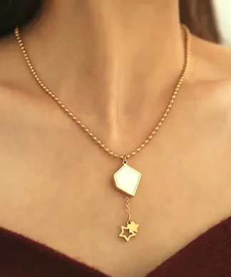 Collier pendentif géométrique doré porté avec chaîne perlée et étoiles