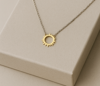 Collier soleil en acier inoxydable doré présenté sur boîte beige